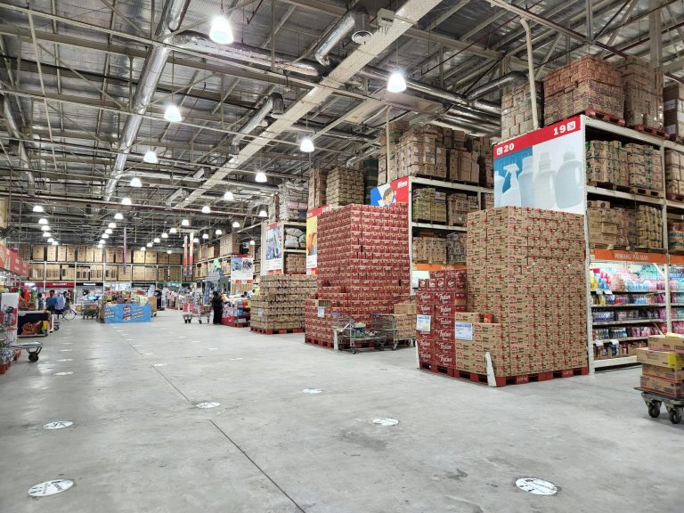 A large warehouse with merchandise organized on shelves and pallets.