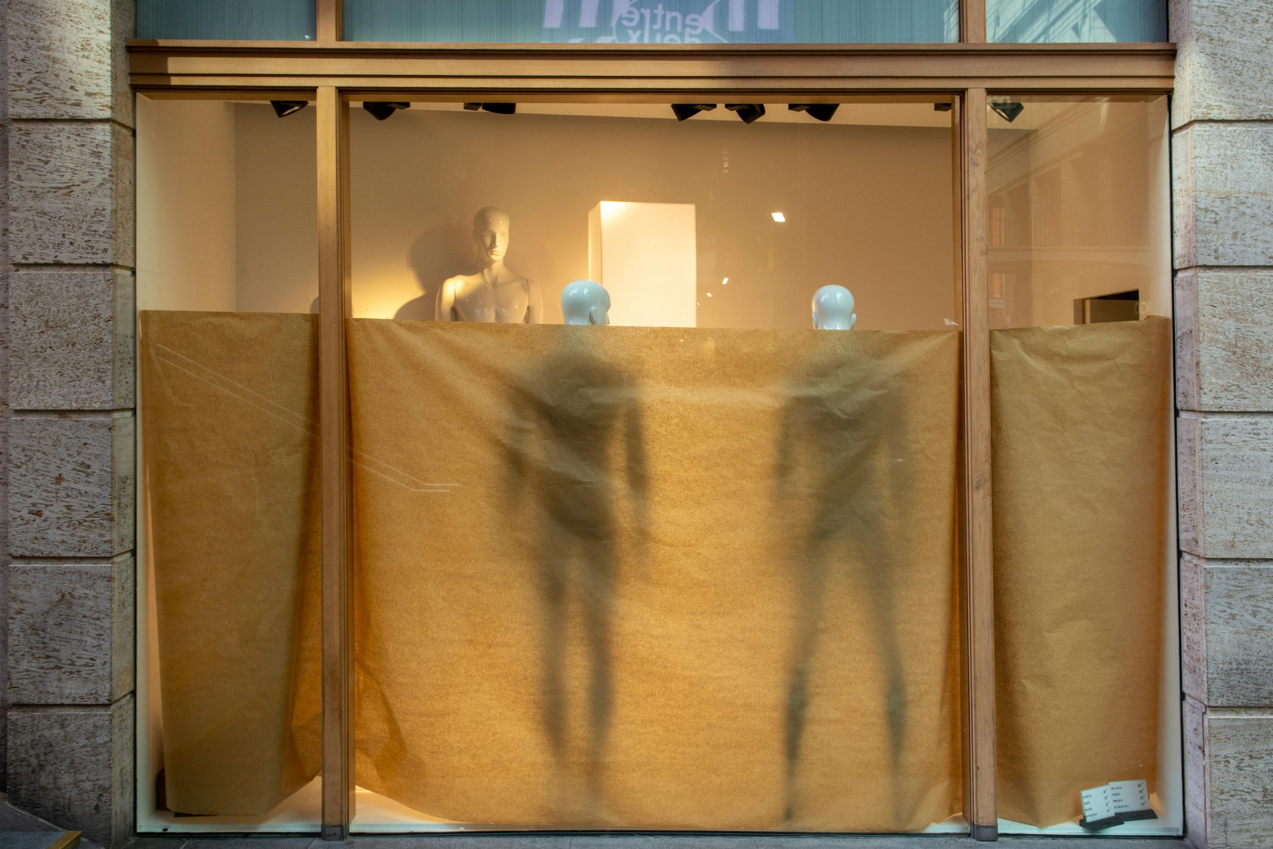 A photo of a partially covered storefront with mannequins inside.